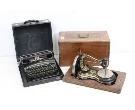 An early 20th century cast iron sewing machine within fitted wooden box together with a vintage typewriter. 
