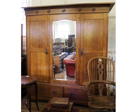 An Art Nouveau light-oak treble wardrobe with shaped cornice, stylised roundels to the frieze, central mirrored door, origina