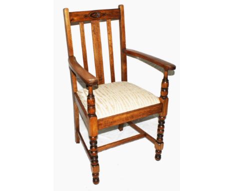 A pair of Arts and Crafts light oak carver chairs with spindle supports, stylised carving to the top rail, shaped arms, drop 
