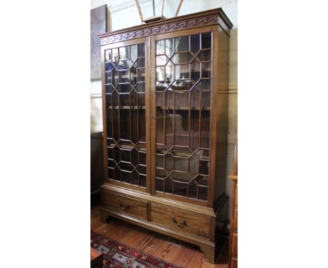 A Georgian-style Chippendale-design mahogany bookcase with shaped cornice, blind fret work to the frieze, twin astragal doors