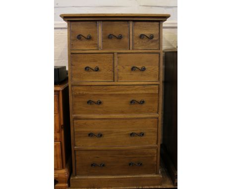 An Hispanic-style light oak chest of five small and three graduated drawers with black-painted metal handles on a square plin