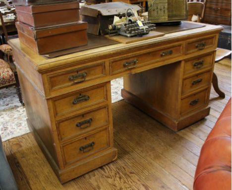 A late 19th century light oak-stained twin pedestal desk with leather inset top, eight short and one long drawer on shaped pl