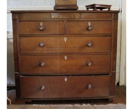 A Victorian oak stained chest of two small and three long graduated drawers with shaped top, ivory escutcheons, turned handle
