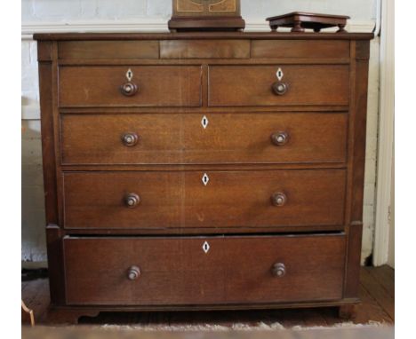 A Victorian oak stained chest of two small and three long graduated drawers with shaped top, ivory escutcheons, turned handle