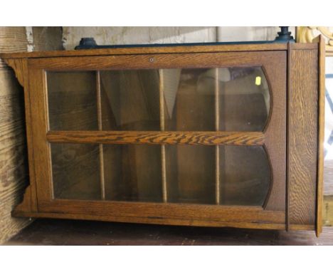 An early 20th century oak stained side cabinet with shaped lift-up top, plain frieze, glazed door with shelved interior, rais