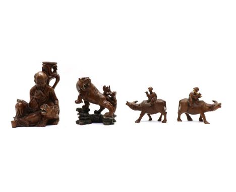 Four Chinese wood carvings, 20th century, comprising: one old man reading a book with a tiger by his side, 25.7cm high, one t