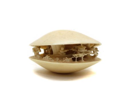 A Japenese ivory shell dream, Meiji period, the bivalve opening to reveal figures in a boat on a river surrounded by pine tre