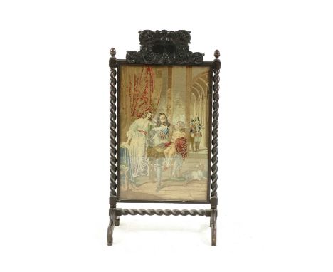 A 19th century carved oak firescreen with ornate cresting, barley twist uprights, splay feet, glazed gros point panel depicti
