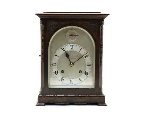 An oak mantel clock, early 20th century, the arched, silvered, dial inscribed 'Harrods Ltd. London', below a slow/fast dial, 