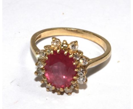 A ruby and diamond cluster ring set in 9 carat gold
