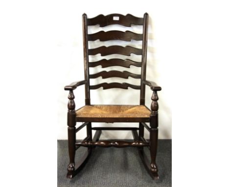 A rush seated and ladder backed rocking chair.