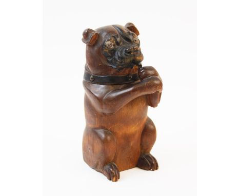 A treen tobacco jar in the form of a dog, 19th century, the seated dog modelled with arms crossed to form a pipe rack, staine