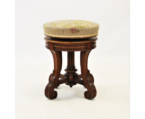 A late Victorian revolving piano stool by Lamb of Manchester, the tapestry covered circular padded seat raised upon a central