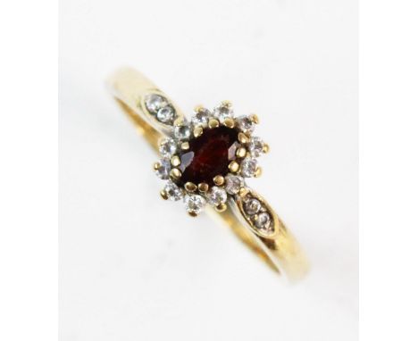 A garnet and white stone cluster ring, the central mixed cut oval garnet with a border surround of white stones, with a furth