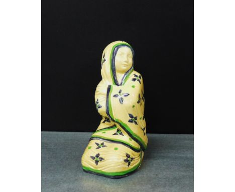 An Ashtead potters figure of a girl modelled seated on her knees and wrapped in a blue floral cloak, has black printed backst