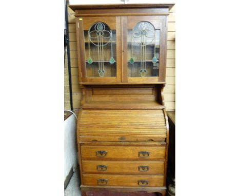 AN ARTS & CRAFTS STYLE OAK BUREAU BOOKCASE, the top with inverted crown over twin glazed doors having stylized stained glass 