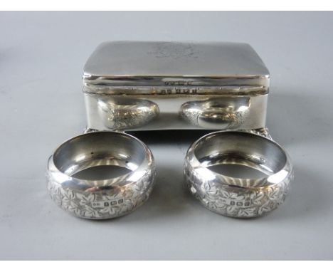 A HALLMARKED SILVER TRINKET BOX and a cased pair of napkin rings, the rectangular box with monogrammed lid and shell formed c