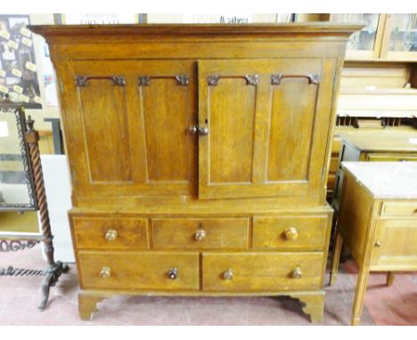 AN EARLY TO MID 19th CENTURY OAK PRESS CUPBOARD, the inverted cornice over two twin panel doors with leaf decoration and turn