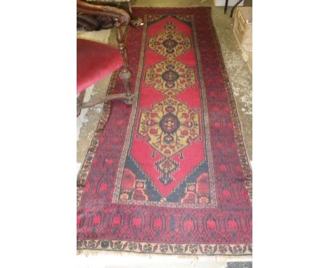 A red ground runner with central gold medallion design, c. 41" x 125"