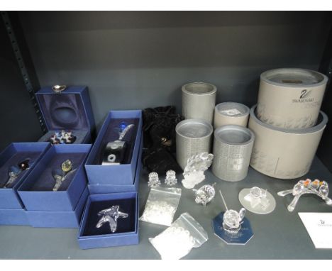 A shelf of Swarovski crystal animal and flower ornaments, including tulips, parrots, etc, most boxed