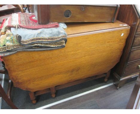 An early/mid 20th century oak dining table having scallop drop flap top on twist gate legs