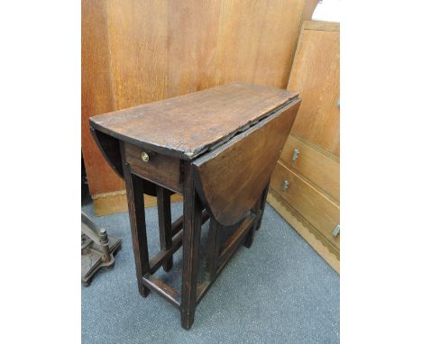 An early 19th century oak vernacular drop leaf table with drawer on square gate legs