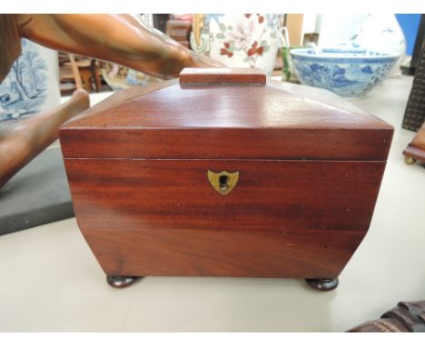 A 19th century mahogany tea caddy of Regency design having ring handles and bun feet
