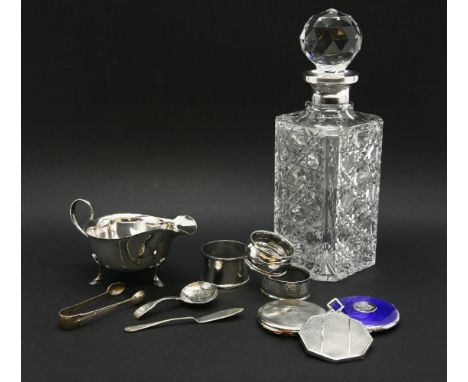 A silver mounted cut glass decanter, a silver sauce boat, three napkin rings, two  compacts, a caddy spoon and a mirror