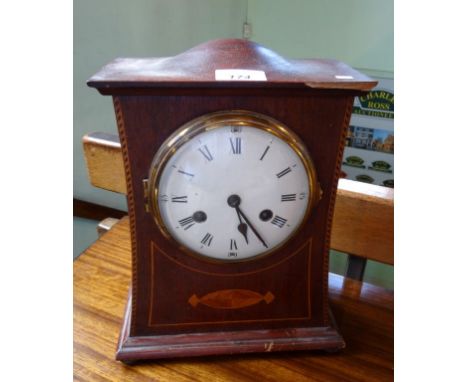 An Edwardian mahogany and inlaid mantel clock, the circular enamel dial bearing Roman numerals (33cm tall).