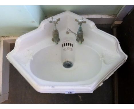 An early to mid-20th century ceramic corner basin, in a cast iron scrolled frame, stamped 'The Oceanic' (57cm wide).