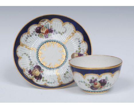 A Worcester ribbed tea bowl and saucer,  later decorated painted with three panels of garlands of fruit and gilt scrolls, bor