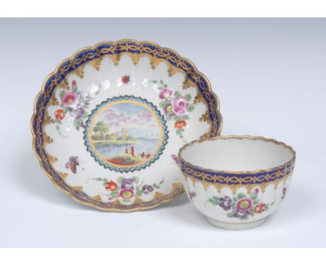 A Worcester Dalhousie style reeded French shaped tea bowl and saucer,  decorated with lakeside views with castles, within tur
