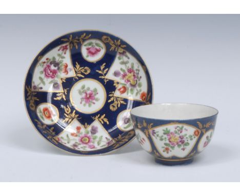 A Worcester tea bowl and saucer, of small size, painted with colourful flowers within fan shaped panels reserved upon a `powd