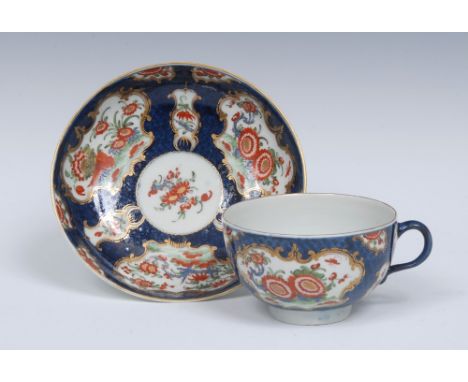 A Worcester teacup and saucer,  painted with alternating fan and vase shaped gilt scroll reserves with stylised flowers and f