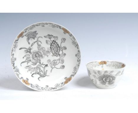 A rare Worcester tea bowl and saucer, pencilled in monochrome with Oriental flower sprays and a moth, within foliate borders 