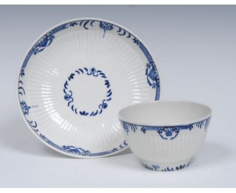 A Worcester reeded  tea bowl and saucer, painted in blue with flower spray within a  formal border,  crescent marks, c.1770 (