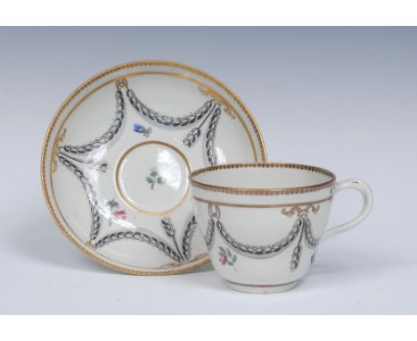 A Worcester Neo-classical double ogee shape cup and saucer, entwined handle, painted with a border of black husk festoons and