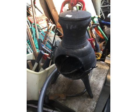 A chimenea / fire pit and a plastic bin containing various garden tools, few saws and a bundle of walking sticks to include h