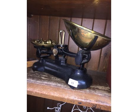 A set of weighing scales with brass plates and imperial dumbbell weights. 