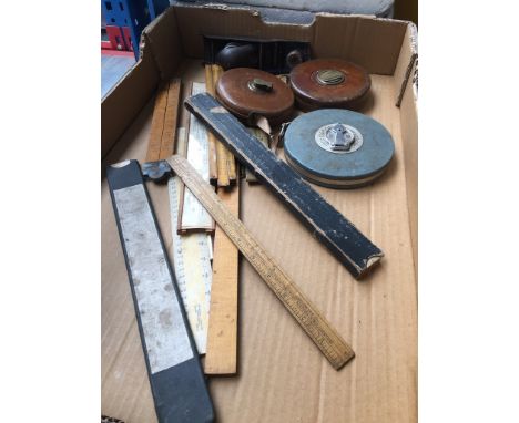 A box containing vintage rules and tape measures 