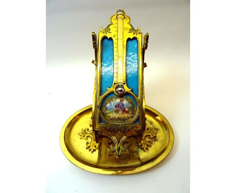 A 19th Century Table Thermometer in gilt brass frame and stand, inset with a painted porcelain panel and on an oval base.  6"