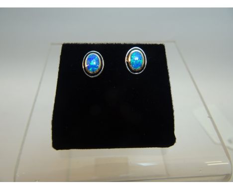 A pair of silver oval Earrings each set with a blue opal.