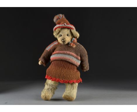 An early British teddy bear, with light golden mohair, black boot button eyes, pronounced muzzle, remains of black stitched n