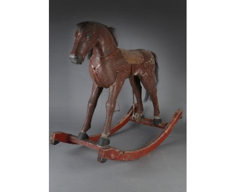 A primitive carved wooden rocking horse, painted brown with carved eyes, leather ears, horse hair mane and tail, straight leg