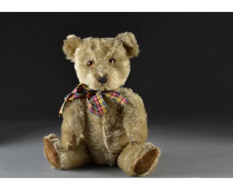 A post-war Chiltern Hugmee musical teddy bear, with blonde mohair, orange and black glass eyes, black stitched nose, mouth an