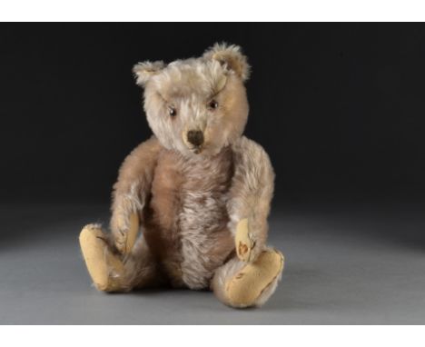 A post-war Steiff teddy bear, with caramel mohair, clear and black glass eyes with brown backs, brown stitched nose, mouth an