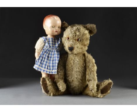 A post-war Chiltern Hugmee teddy bear, with dark blonde mohair, orange and black glass eyes, black stitched nose, mouth and c