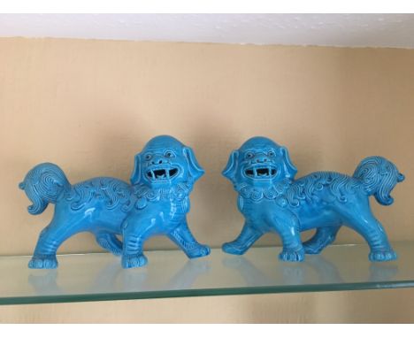 A pair of finely crafted Chinese turquoise-glazed ceramic Foo Dogs, dating to the 1920s. Each guardian dog is depicted in a s