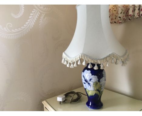 A stunning Moorcroft ceramic lamp featuring a rich cobalt blue glaze adorned with hand-painted floral motifs in white and gre