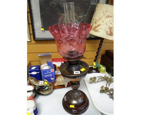 An Art Nouveau antique oil lamp on a pottery base with cranberry glass shade